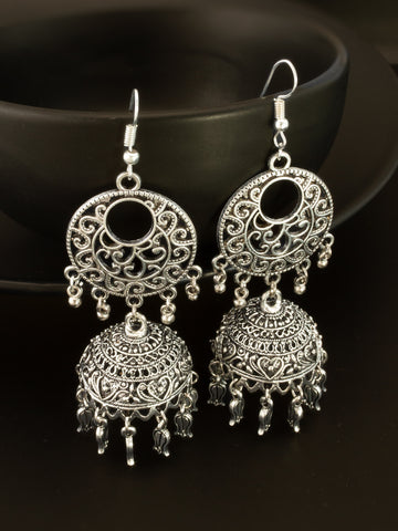 A pair of silver-toned filigree dangle earrings with ornate circular and bell-shaped details, displayed against a dark background.