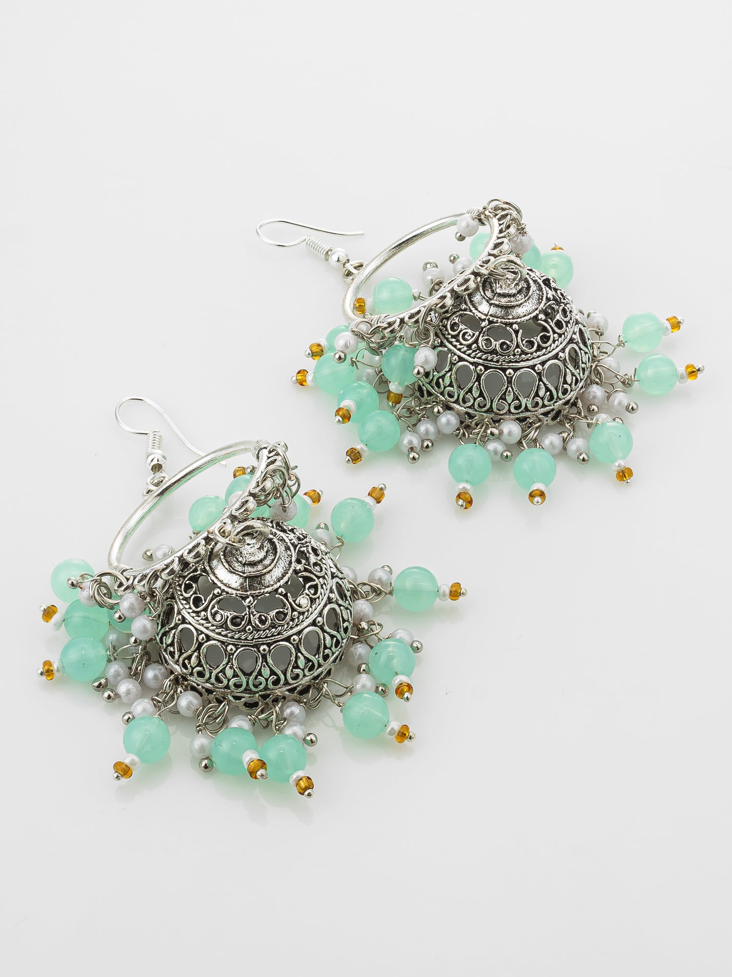 A pair of silver-toned filigree jhumka earrings with dangling mint green beads and small gold and white pearl accents, displayed on a clean white background.