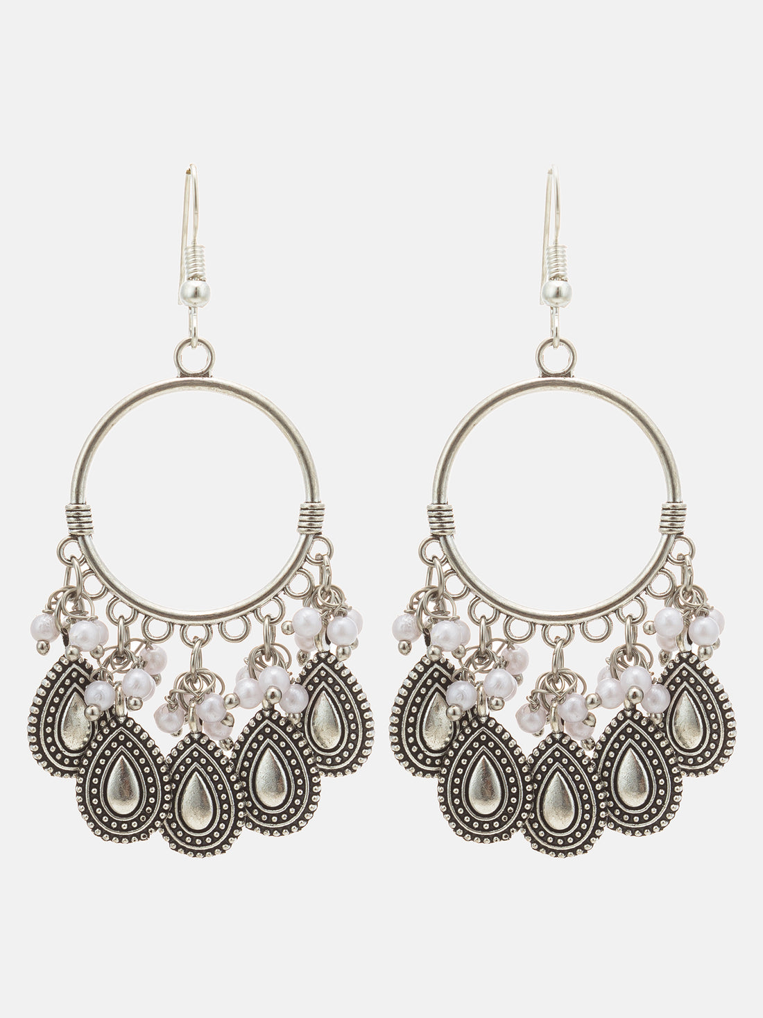 A pair of silver-toned bohemian dangle earrings with white pearl-like beads, displayed on a dark brown background.