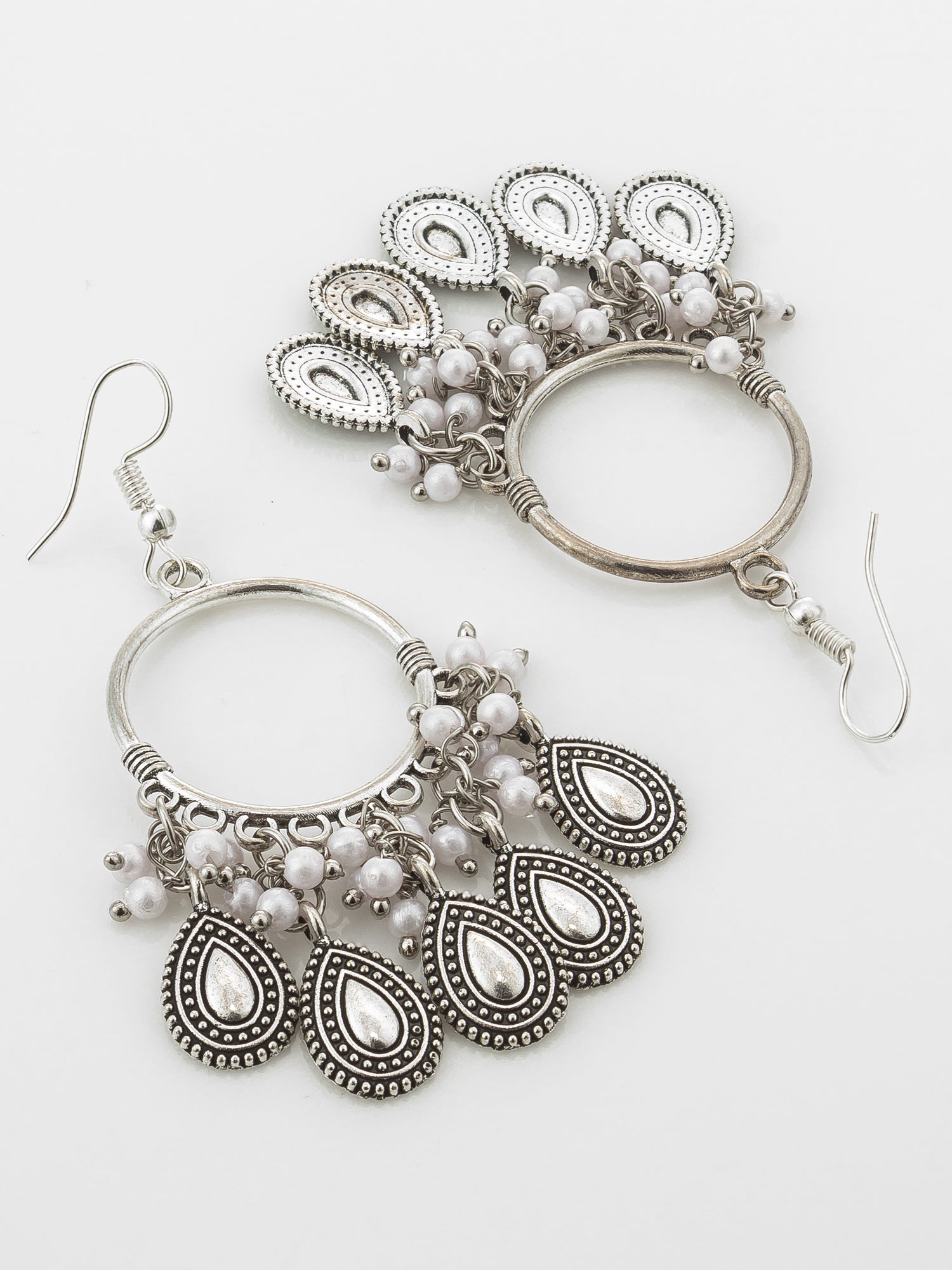 A pair of silver-toned bohemian dangle earrings with teardrop-shaped metal charms, small white pearl beads, and circular hoop details, displayed on a clean white background.