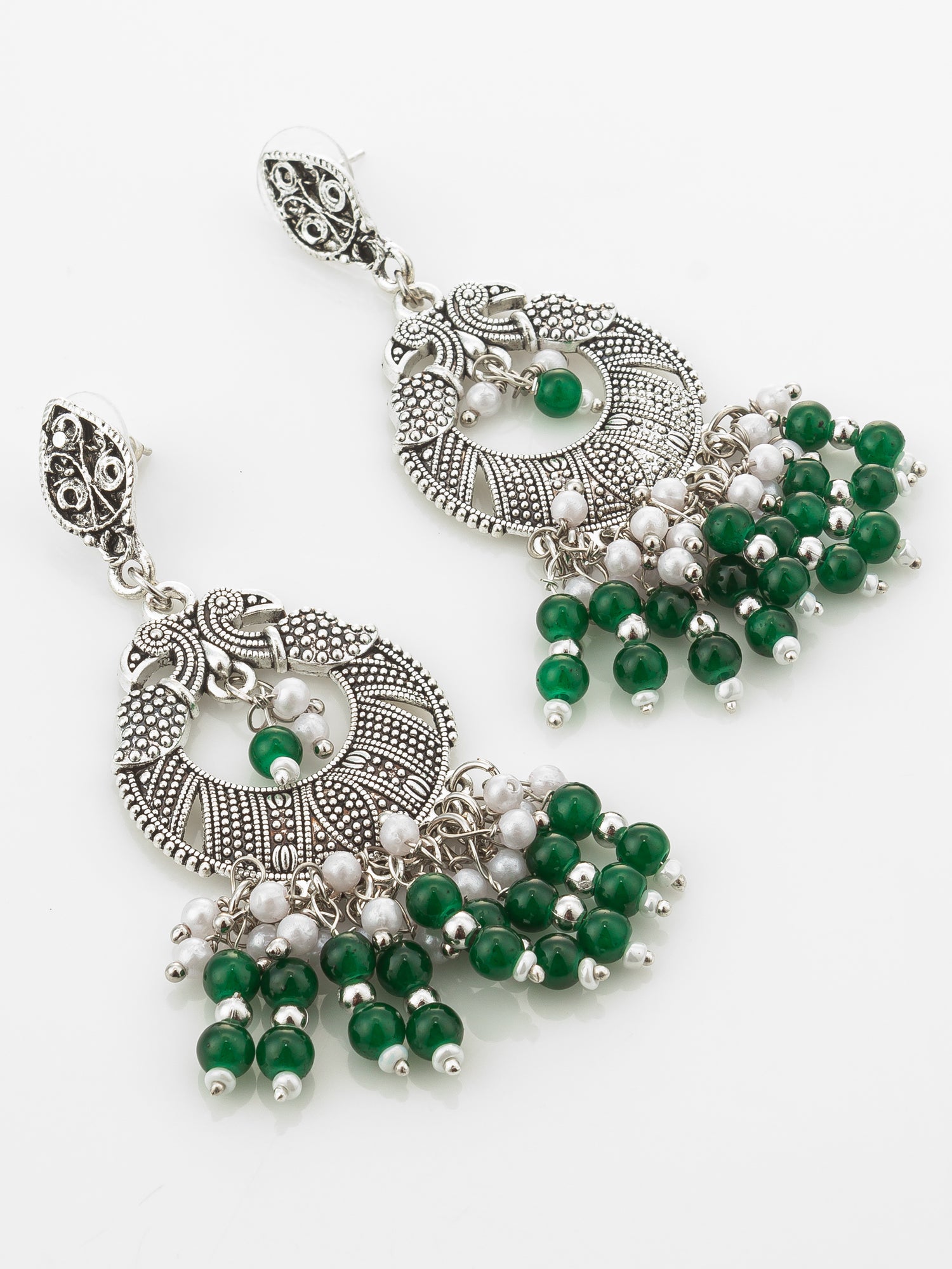 A pair of ornate silver-toned dangle earrings with green and white bead details, displayed on a clean white background.