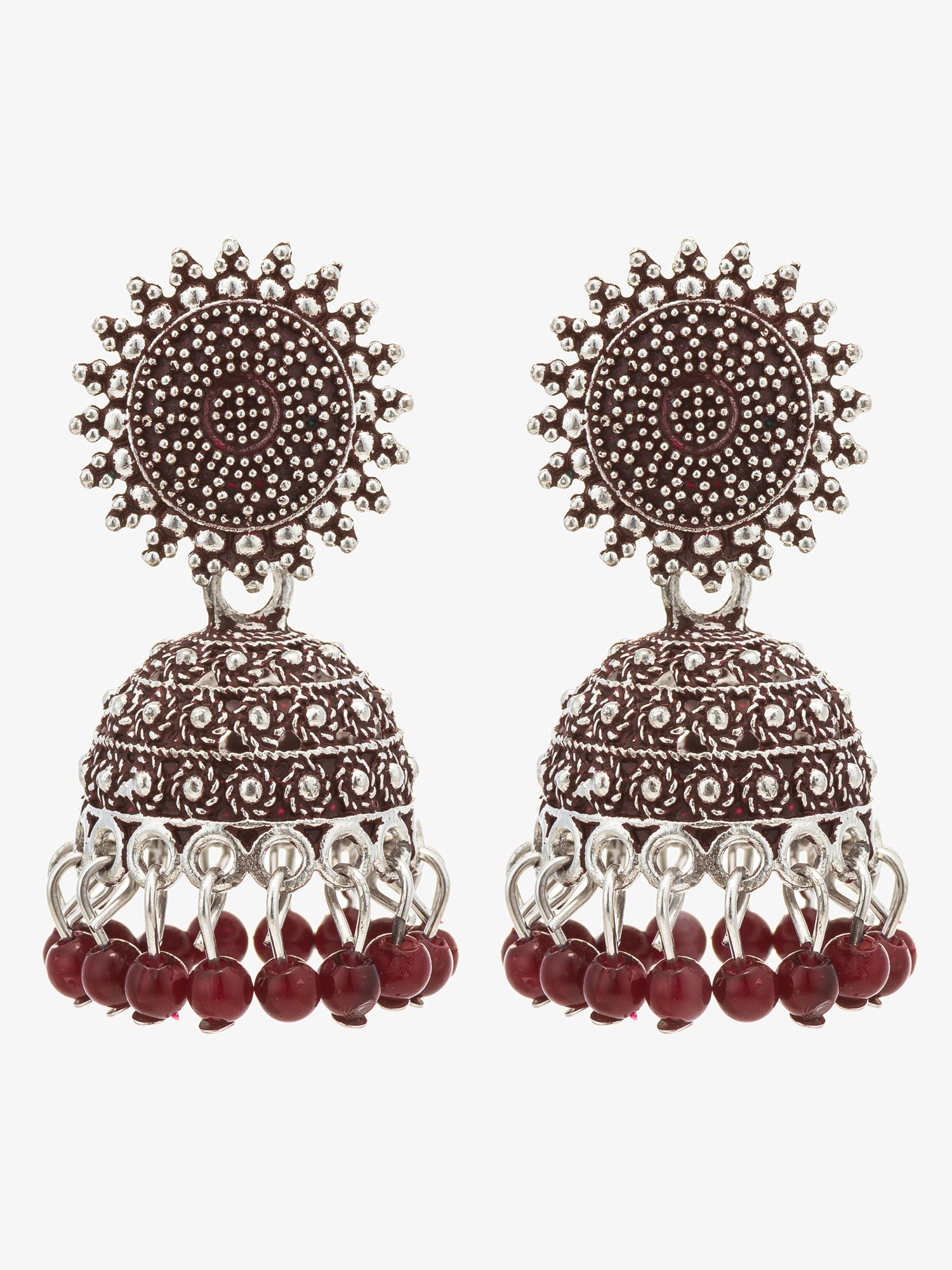 A pair of ornate Indian jhumka earrings with silver-toned filigree work, dark red circular studs, and dangling dark red bead chains, shown against a plain light gray background.