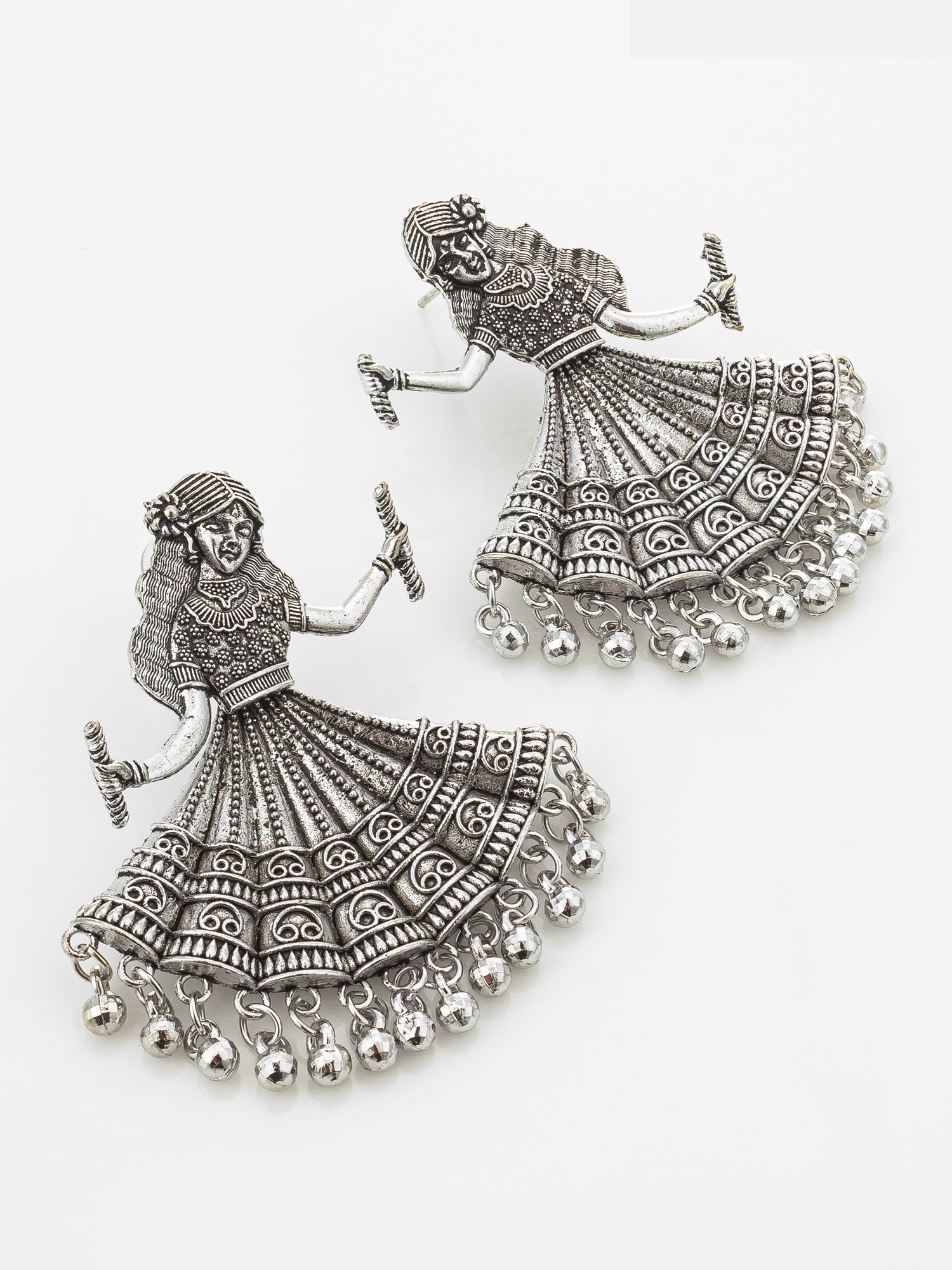 A pair of silver-toned Indian-style jhumka earrings featuring detailed filigree designs of dancing women with dangling bell chains, shown on a plain white background.