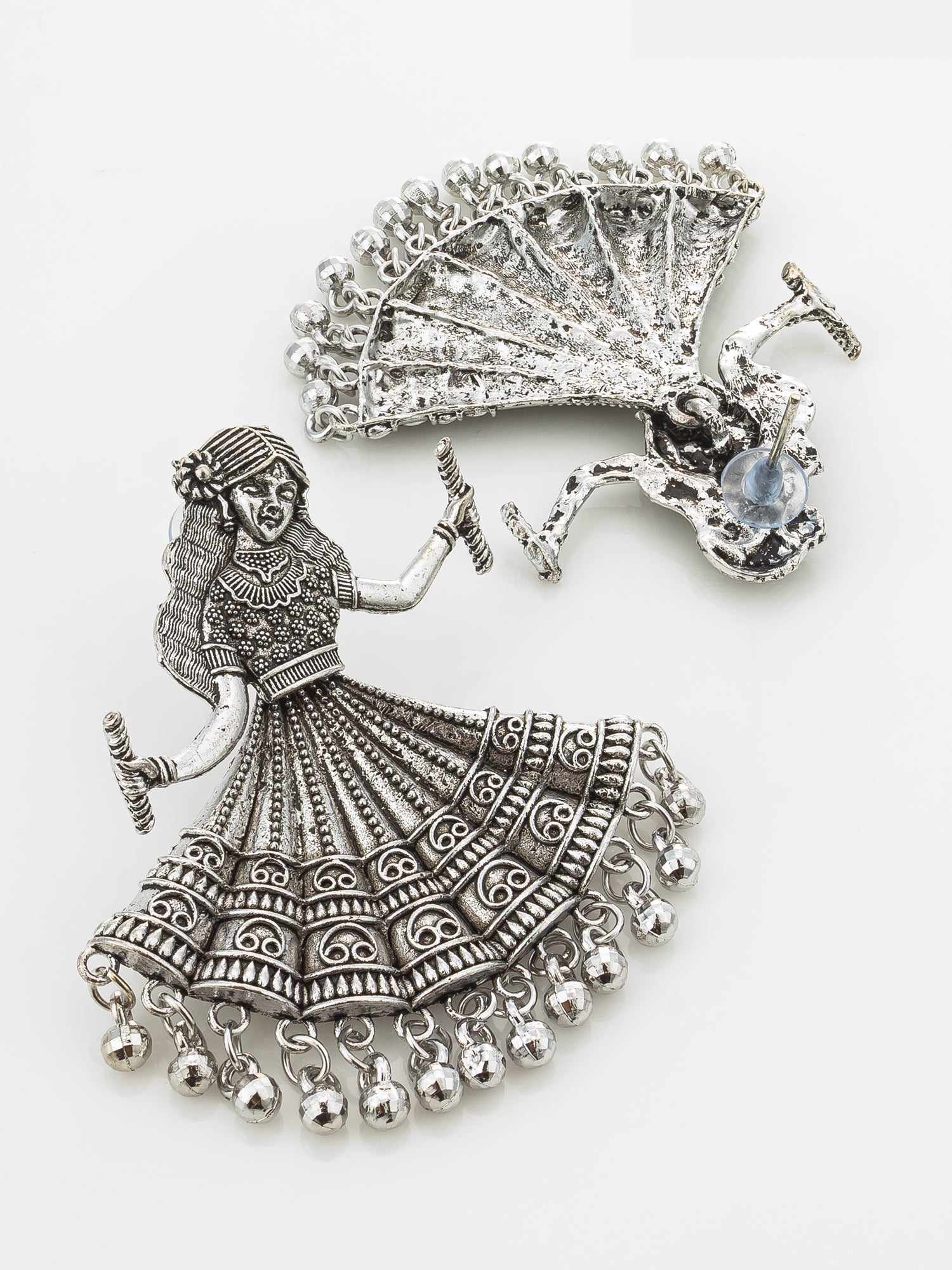 A pair of silver-toned jewelry charms on a white background, featuring a detailed dancing woman with a patterned skirt and a peacock.