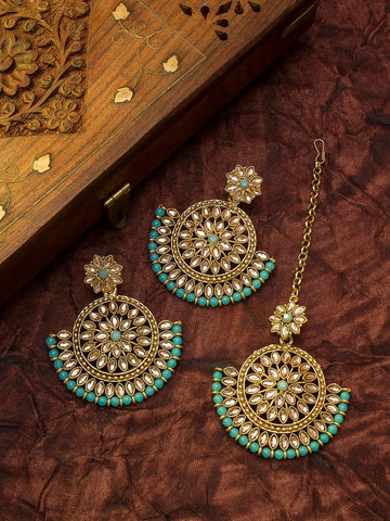 Ornate gold and turquoise earrings on a brown textured surface with an ornate wooden box in the background.