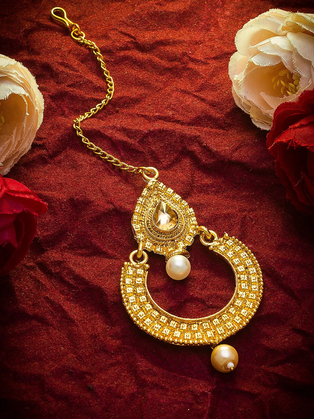 Gold necklace with a pearl pendant on a red fabric background