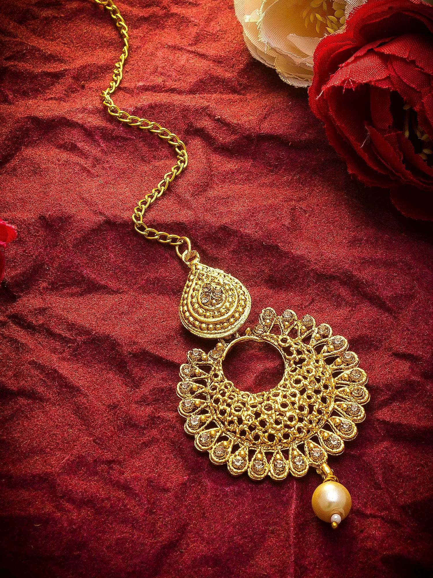Gold necklace with intricate design on a red fabric background
