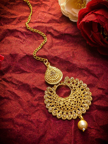 Gold necklace with intricate design on a red fabric background