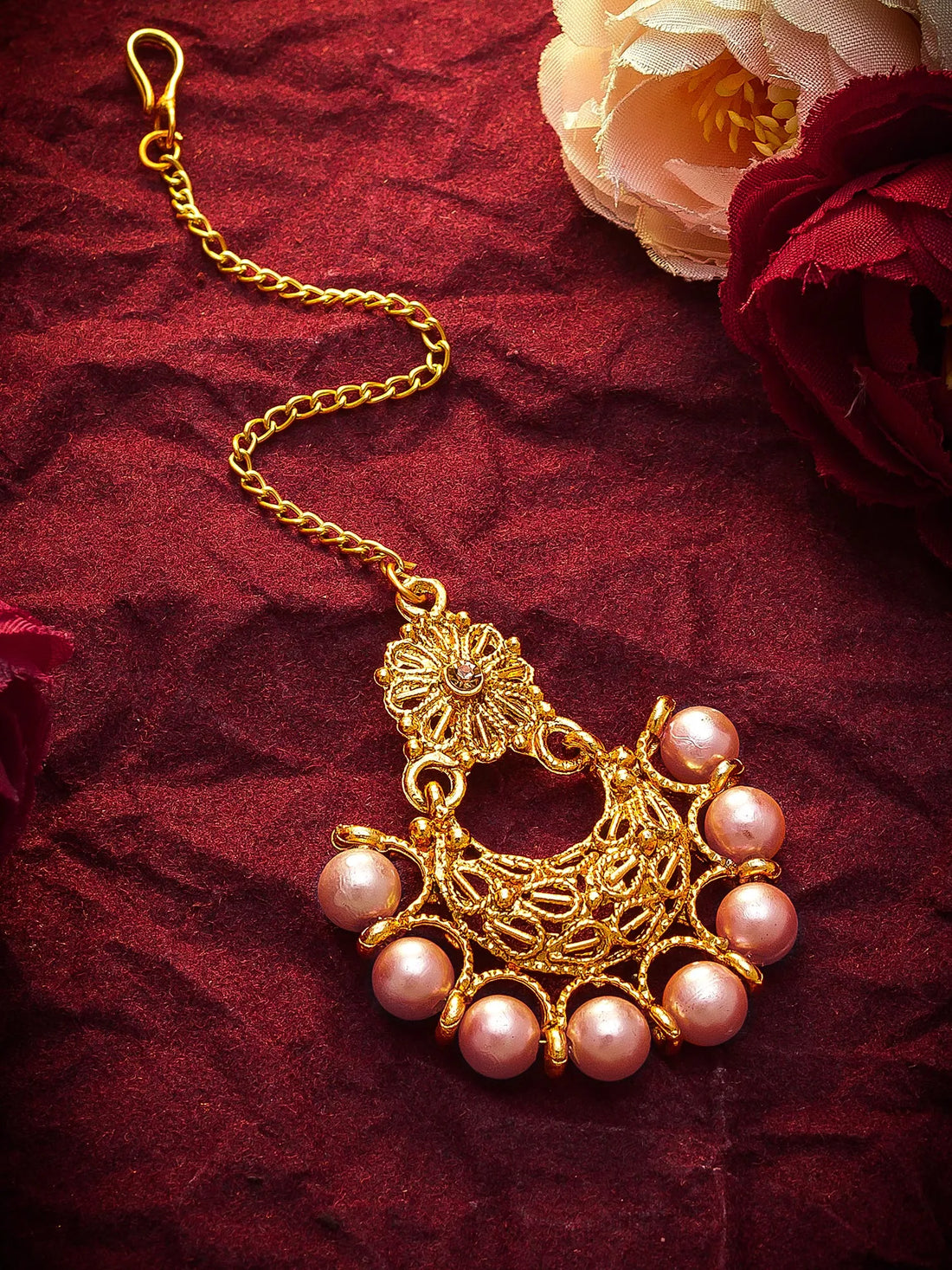 Gold necklace with pink pearls on a red fabric background