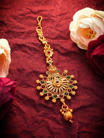 Gold decorative hanging ornament with gemstones on a red fabric background with flowers.