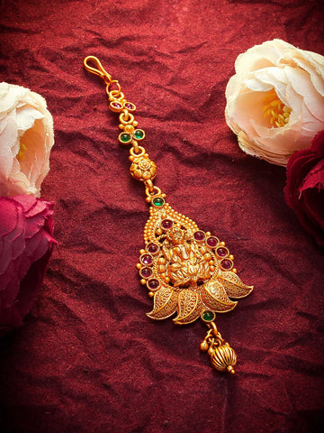 Gold necklace with gemstones on a red fabric background with flowers
