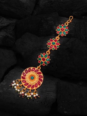 Decorative gold bracelet with red and green gemstones on a dark background