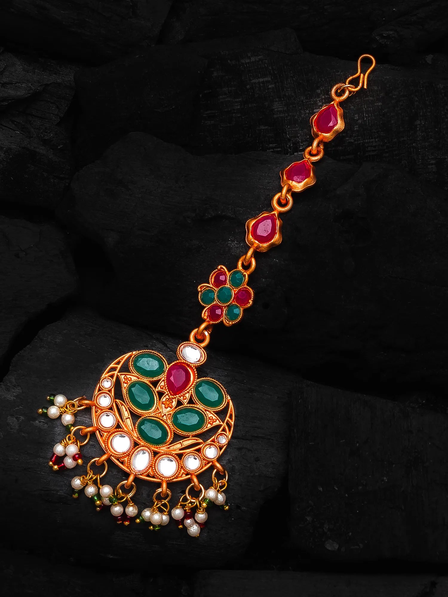 Decorative jewelry piece with gemstones and pearls on a dark background