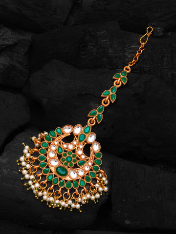 Decorative gold, green, and pearl pendant on a dark background