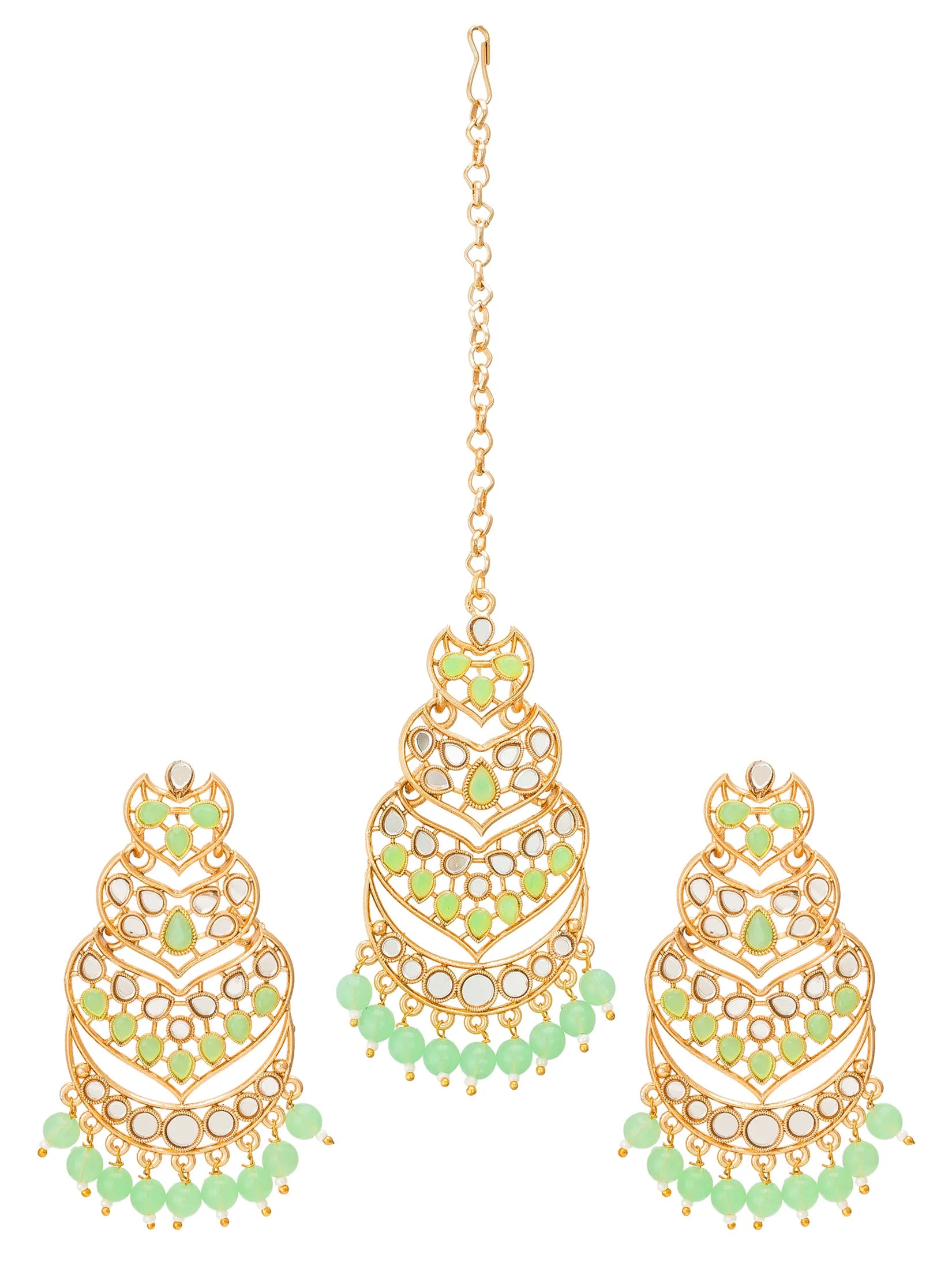 Gold-plated maang tikka and matching pair of dangle earrings decorated with light green stones and white crystal-like accents, shown on a plain white background.
