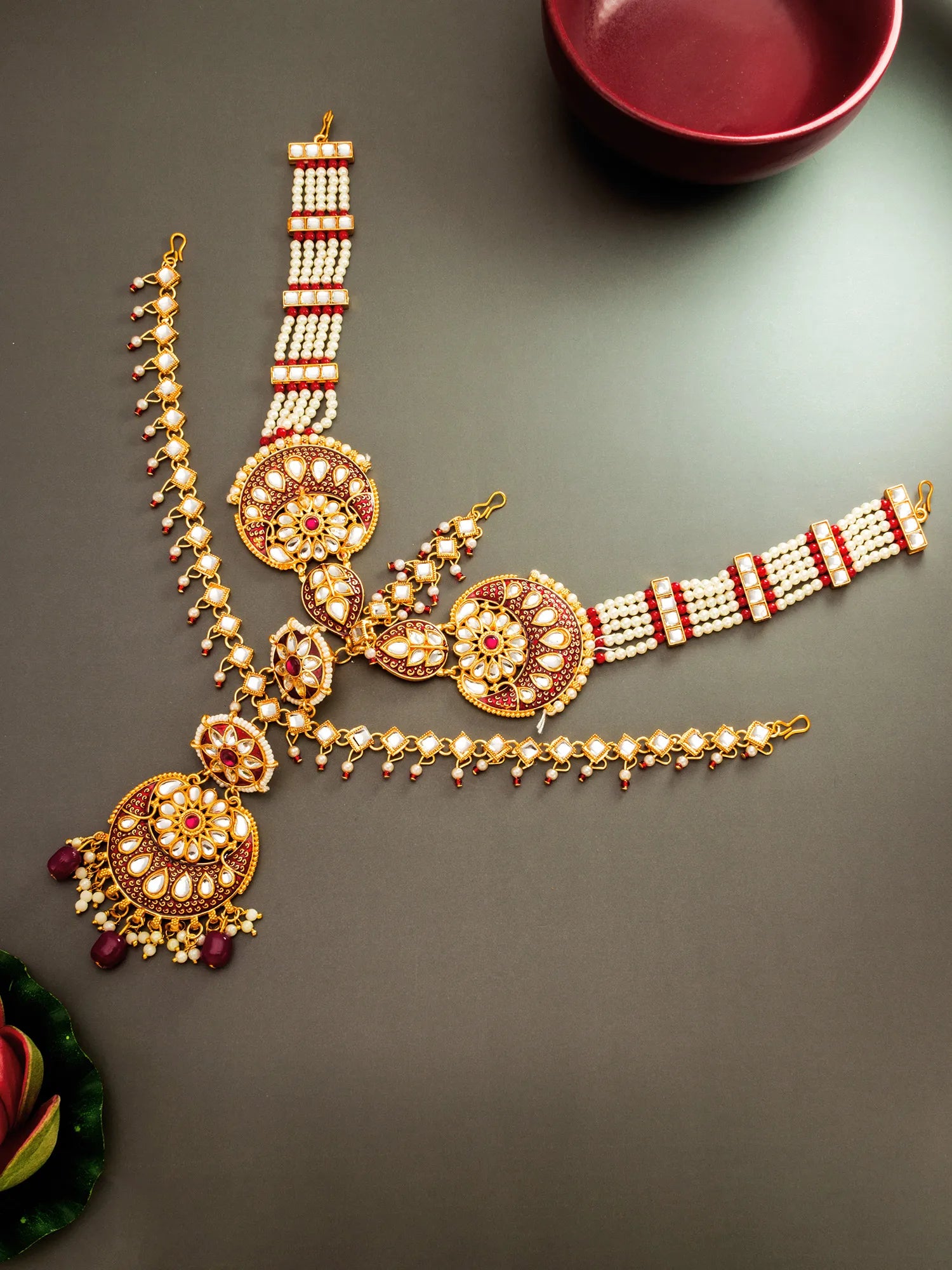 Decorative gold necklace with red and white accents on a dark surface