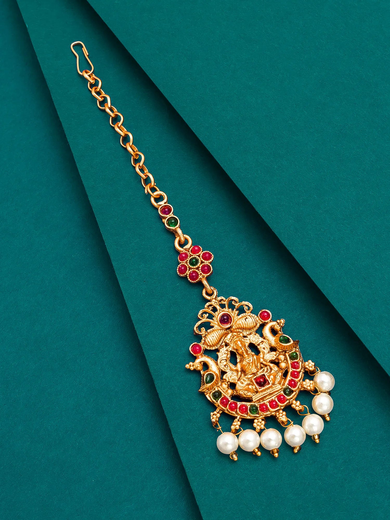 Gold necklace with pearls and gemstones on a green background