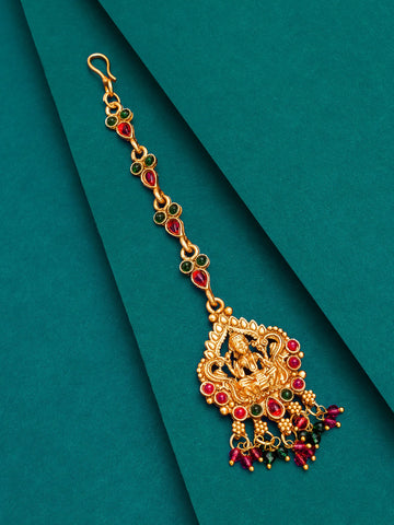 Gold and red gemstone decorative hair accessory on a teal background