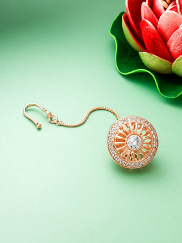 Rose gold earring with intricate design on a light green background