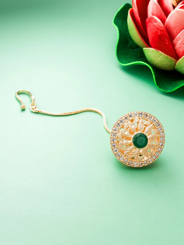 Gold earring with green gemstone on a light green background