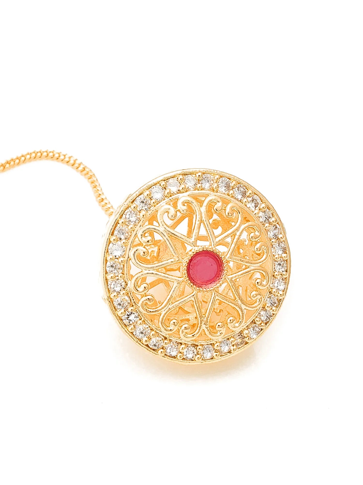 Gold pendant with a red gemstone and intricate design on a white background