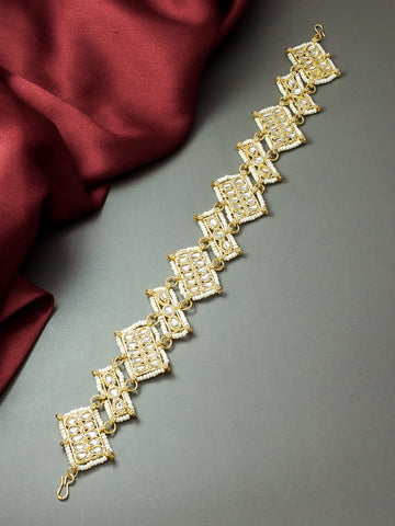 Gold bracelet on a gray surface with a red fabric background