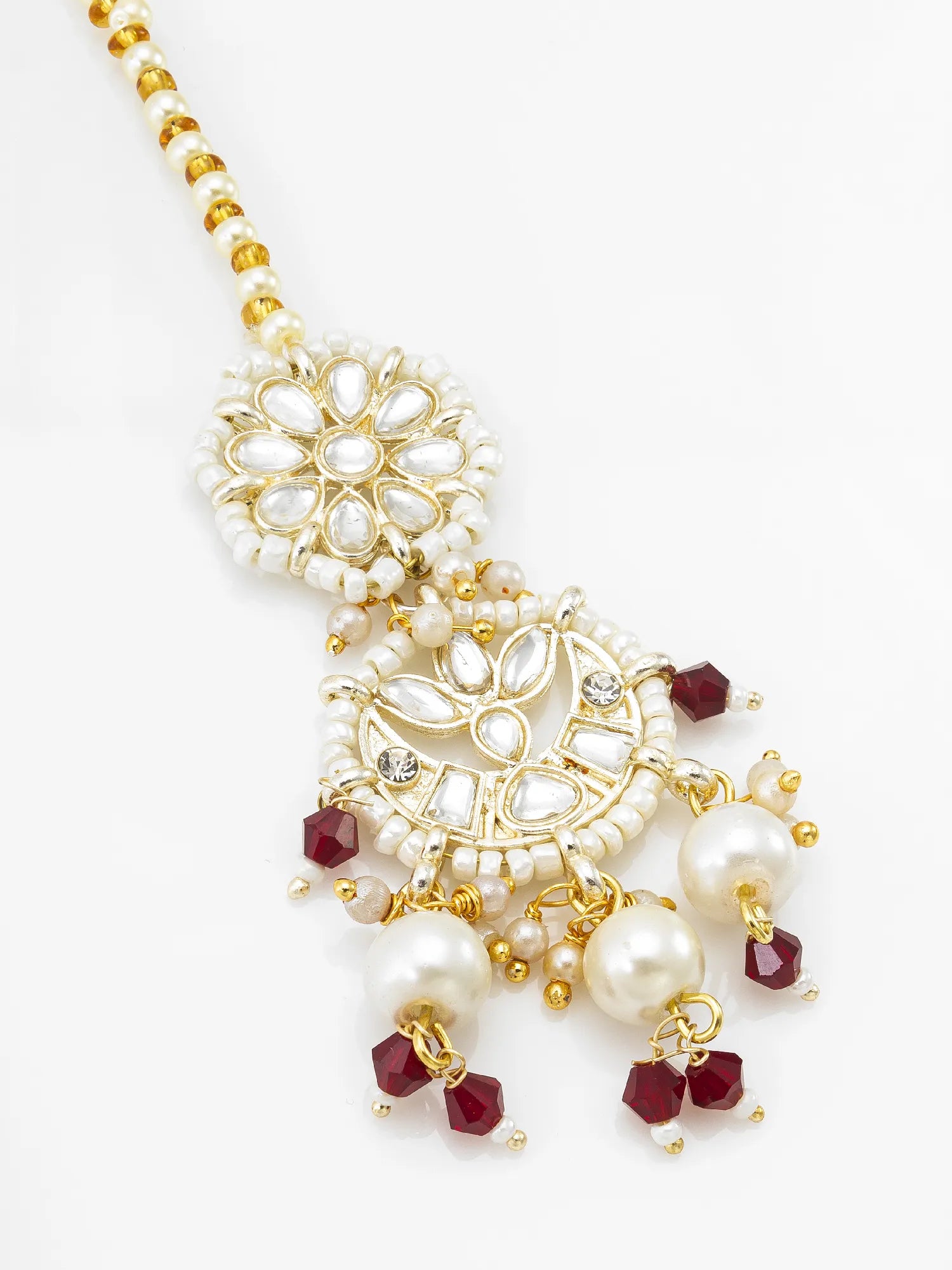 Gold-plated traditional Indian jewelry piece featuring white faux pearls, clear rhinestones, and deep red faceted beads, displayed on a clean white background.