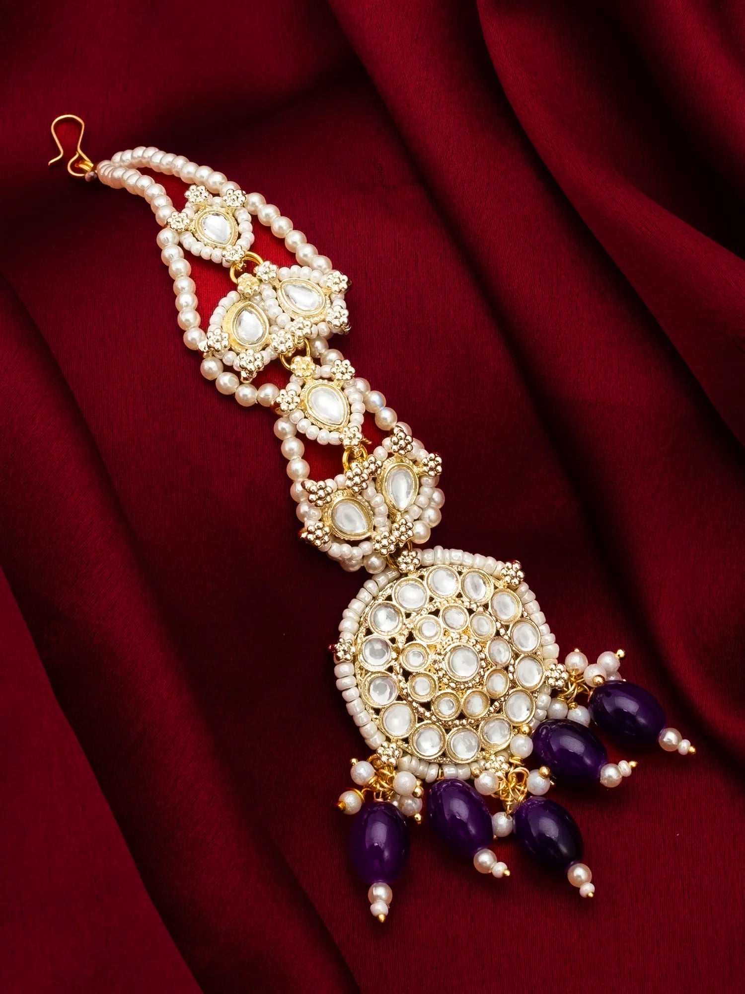Ornate necklace with purple beads on a red fabric background