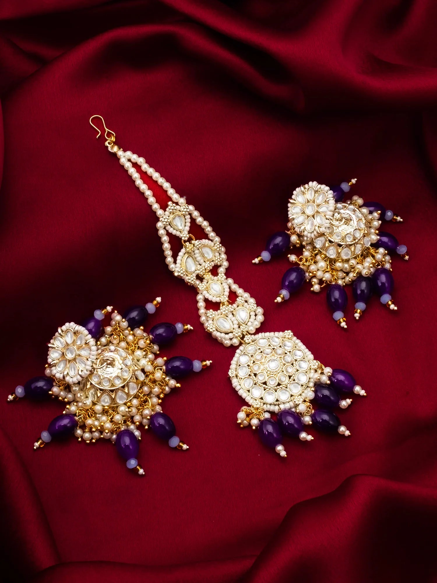 Ornate gold and purple jewelry set on a red fabric background