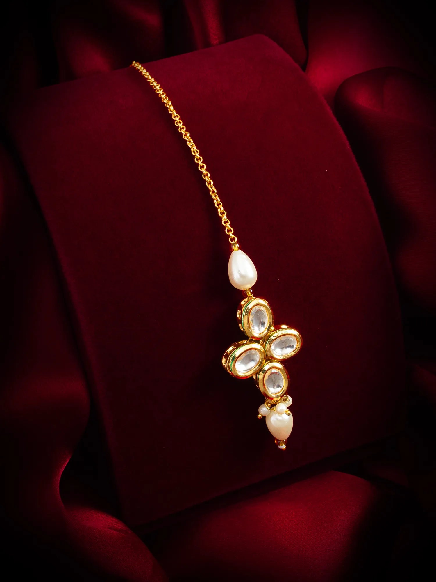 Gold necklace with a floral pendant on a red fabric background