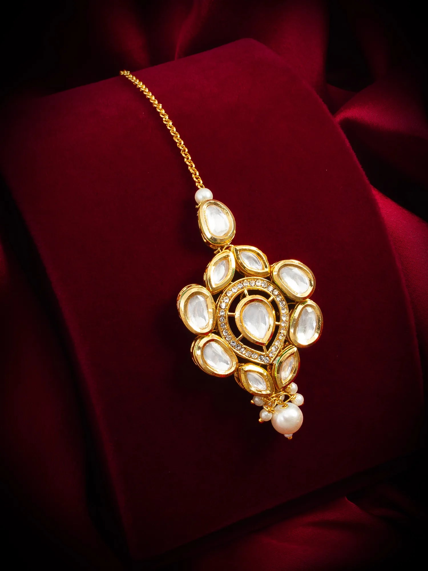 Decorative gold necklace with pearls on a red fabric background