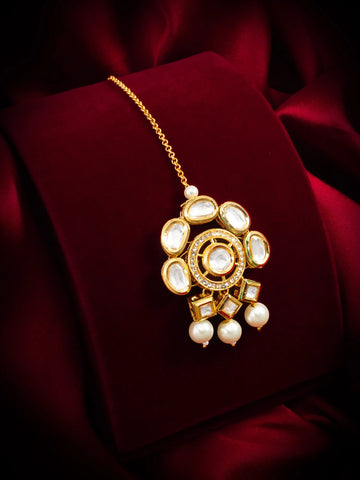 Gold necklace with a decorative pendant on a red fabric background