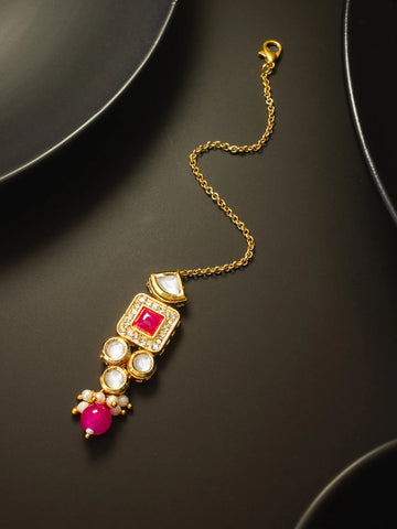 Gold necklace with red and white gemstones on a dark surface
