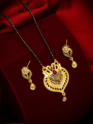 Gold-toned traditional Indian jewelry set featuring a necklace with a detailed heart-shaped pendant, a black beaded chain, and matching drop earrings, displayed on a rich red satin background.