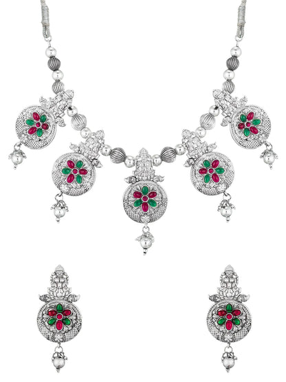 A silver-toned traditional Indian jewelry set featuring a necklace and matching earrings, decorated with red and green enamel floral motifs and clear stones.