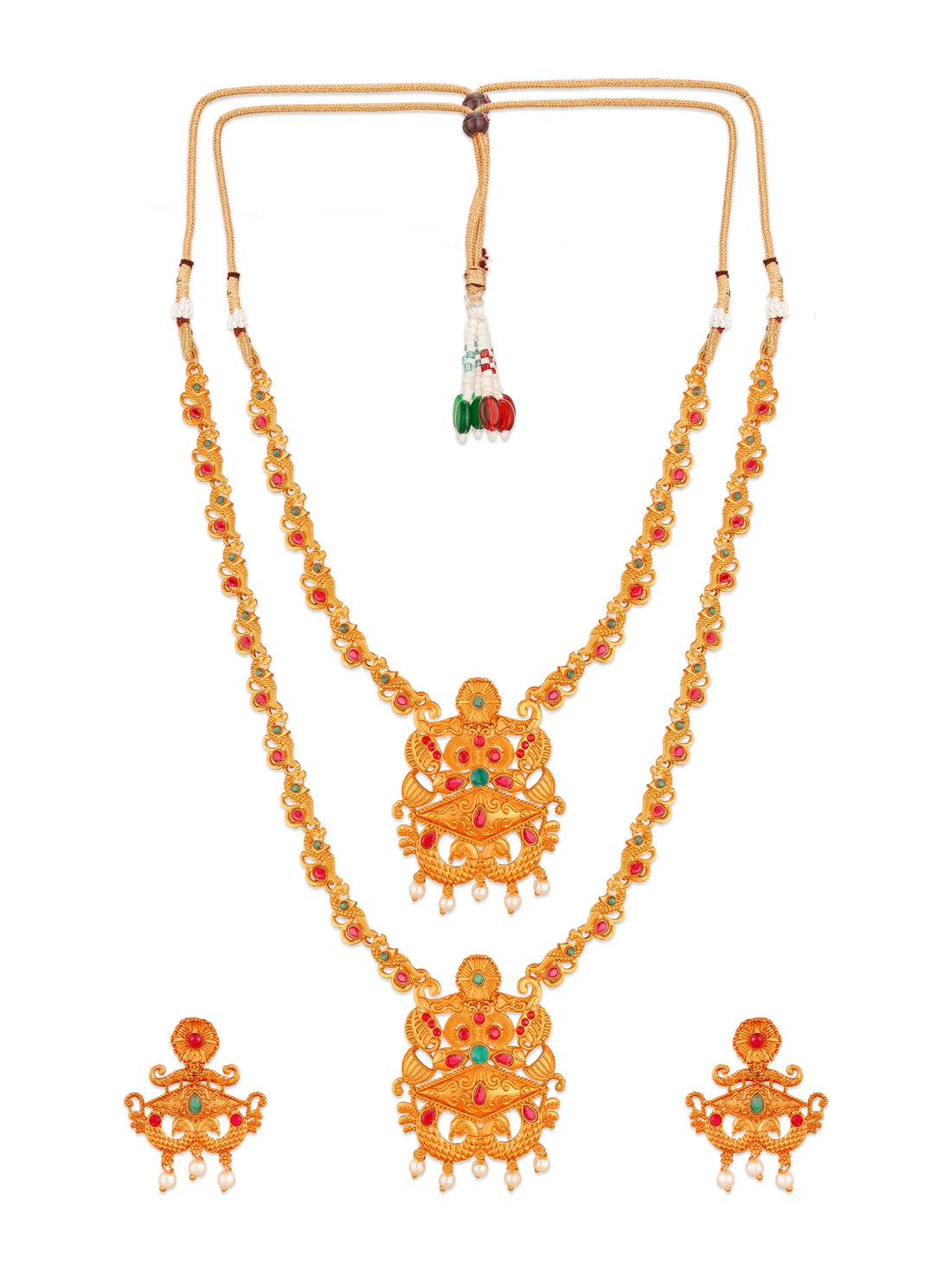 An ornate gold jewelry set featuring a necklace, pendant, earrings, and matching bracelet, decorated with red and green stones and small pearl-like drops, displayed on a carved dark wooden box over a red fabric background.