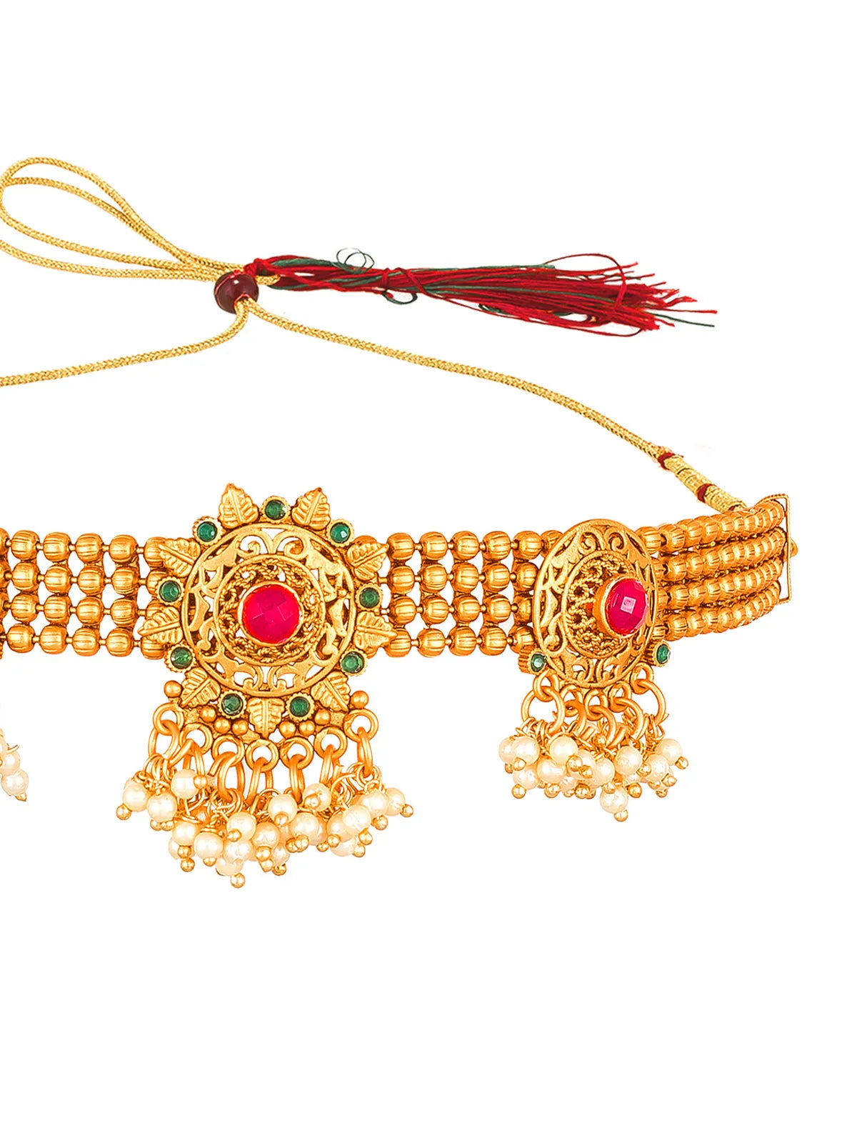 Gold-toned traditional jewelry piece with intricate filigree, red gemstone centers, green stone accents, and dangling pearl-like beads, shown on a plain white background.