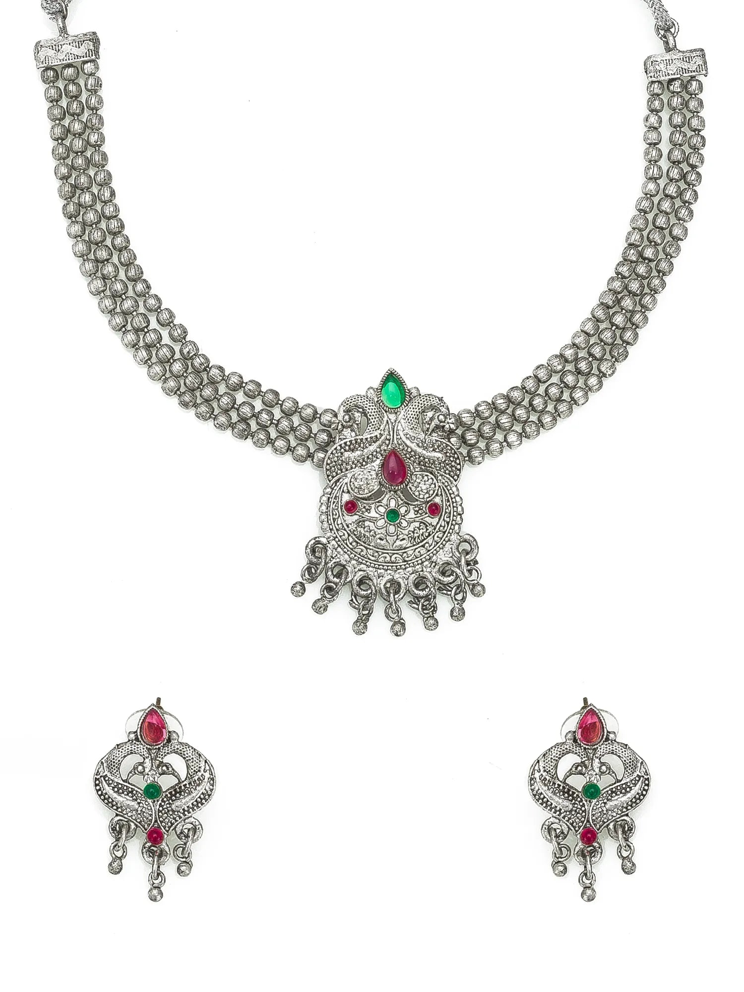 A traditional Indian jewelry set featuring a silver-toned multi-strand necklace with a detailed central pendant and matching drop earrings, embellished with red and green stones on a white background.