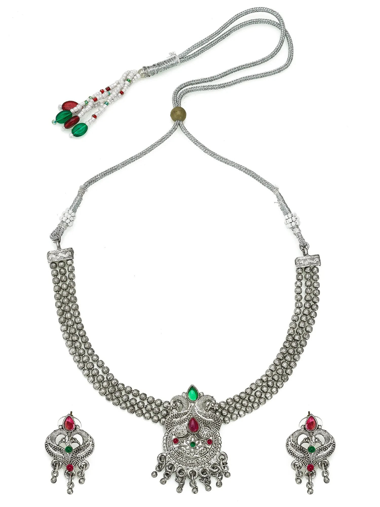 A traditional Indian silver-toned jewelry set featuring a necklace with a detailed central pendant, matching earrings, and a beaded tassel on a white background.