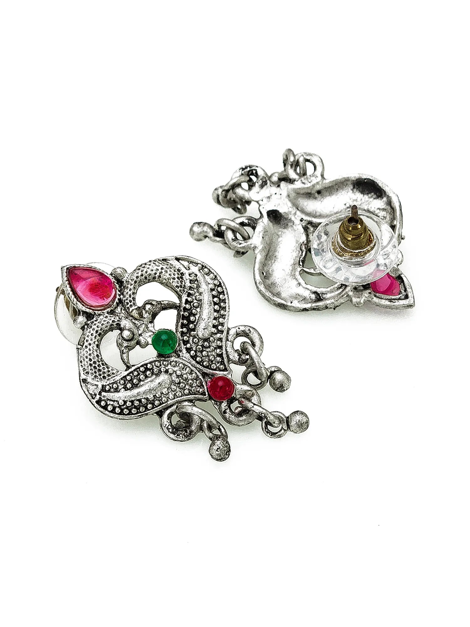 A pair of silver-toned traditional Indian earrings with detailed filigree work, featuring pink gemstones, a green stone, and a central gold accent on a plain white background.