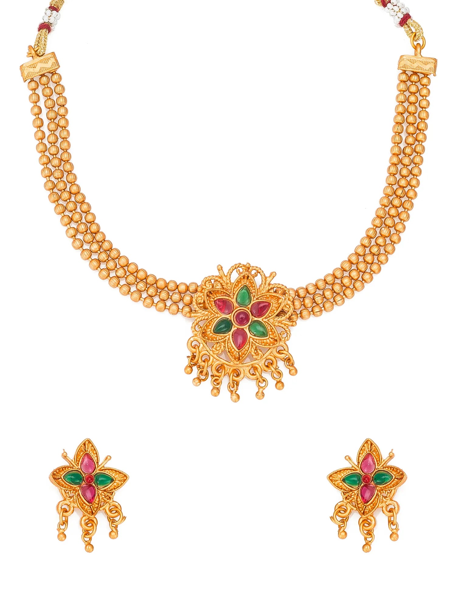 Gold-toned traditional necklace and matching earrings set with a central floral motif accented by red and green stones, shown on a plain white background.