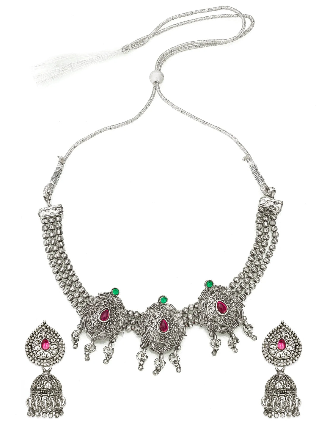 Silver-toned traditional Indian jewelry set featuring a choker necklace, matching earrings, and a waist chain, embellished with silver filigree, beaded borders, and red and green stone accents, displayed on a draped black fabric background.