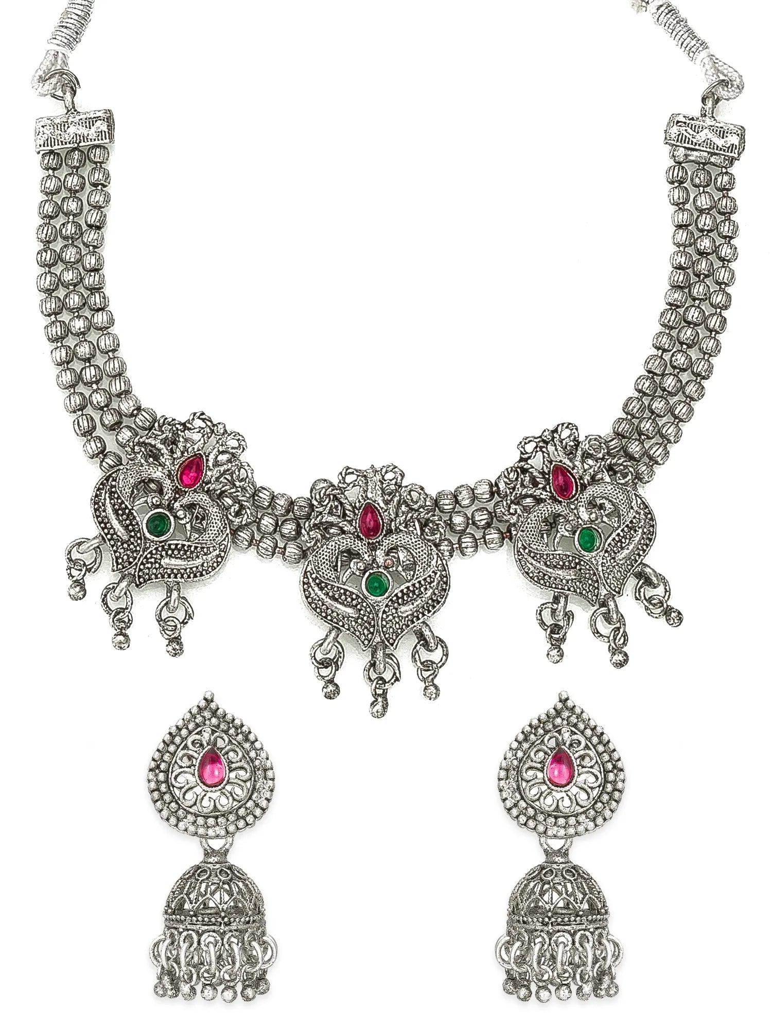 Silver-toned traditional Indian jewelry set featuring a necklace and matching earrings with ornate filigree work and small red and green stone accents, shown on a plain white background.