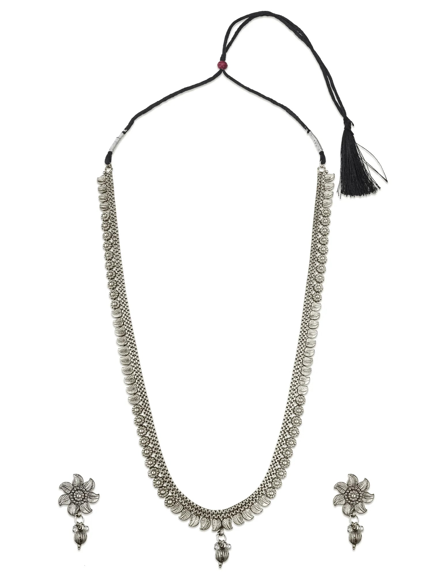 A silver-toned traditional necklace with matching flower-shaped earrings, displayed on a plain white background. The necklace features a textured silver chain, a black cord, and a black tassel.