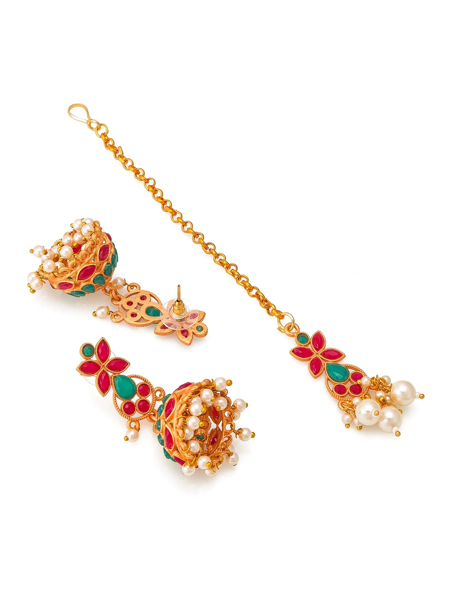 Gold-plated Indian traditional jewelry set featuring a maang tikka with a chain, a jhumka earring, and a matching nose chain, decorated with red and green enamel, white faux pearls, and gold-toned metalwork on a white background.