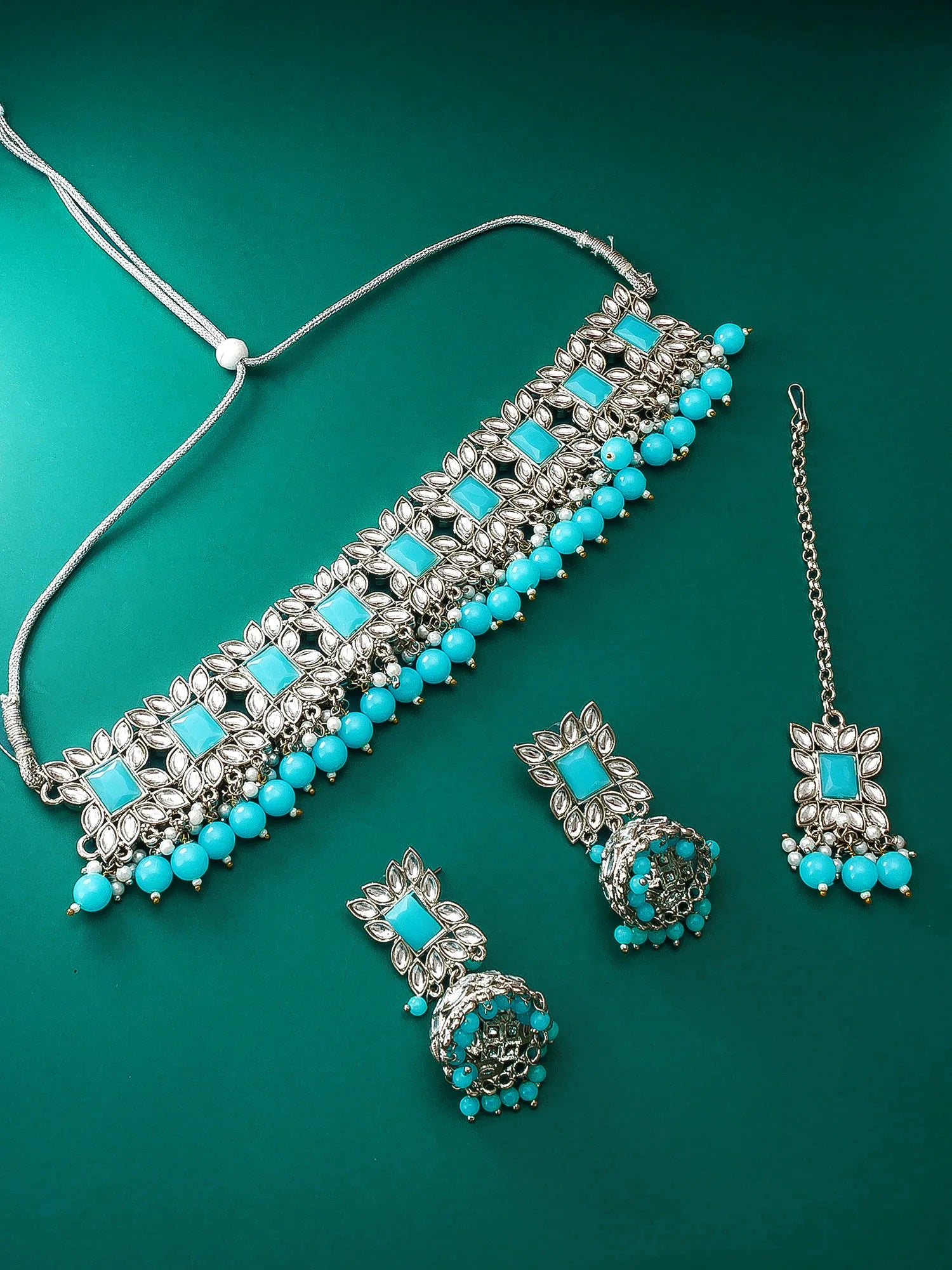 Jewelry set with necklace, earrings, and tikka on a green background