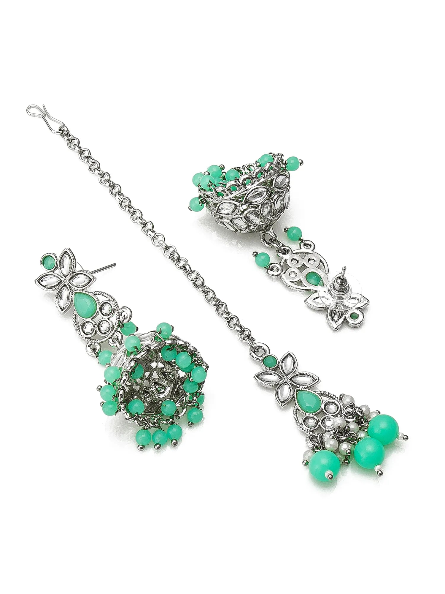 A silver-toned traditional Indian jewelry set featuring a chain with matching dangling earrings and a headpiece, embellished with green stones and beads.