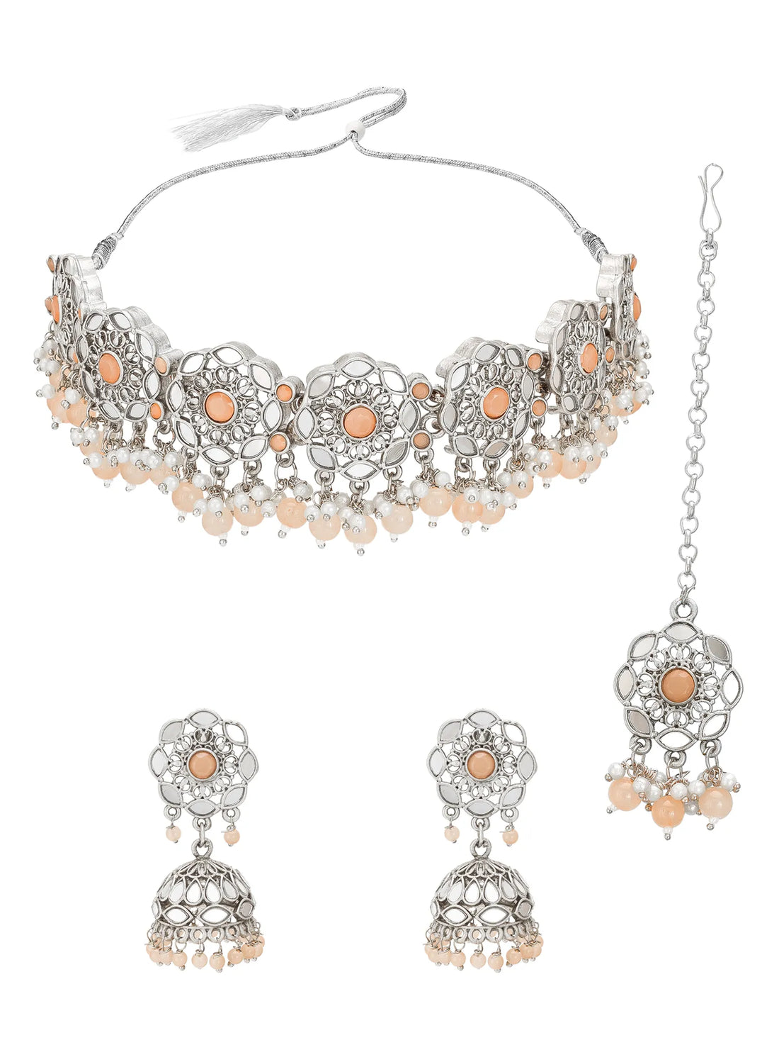 Silver-toned Indian jewelry set featuring a choker necklace, matching earrings, and a maang tikka with peach-colored stones, displayed on a red satin fabric background.