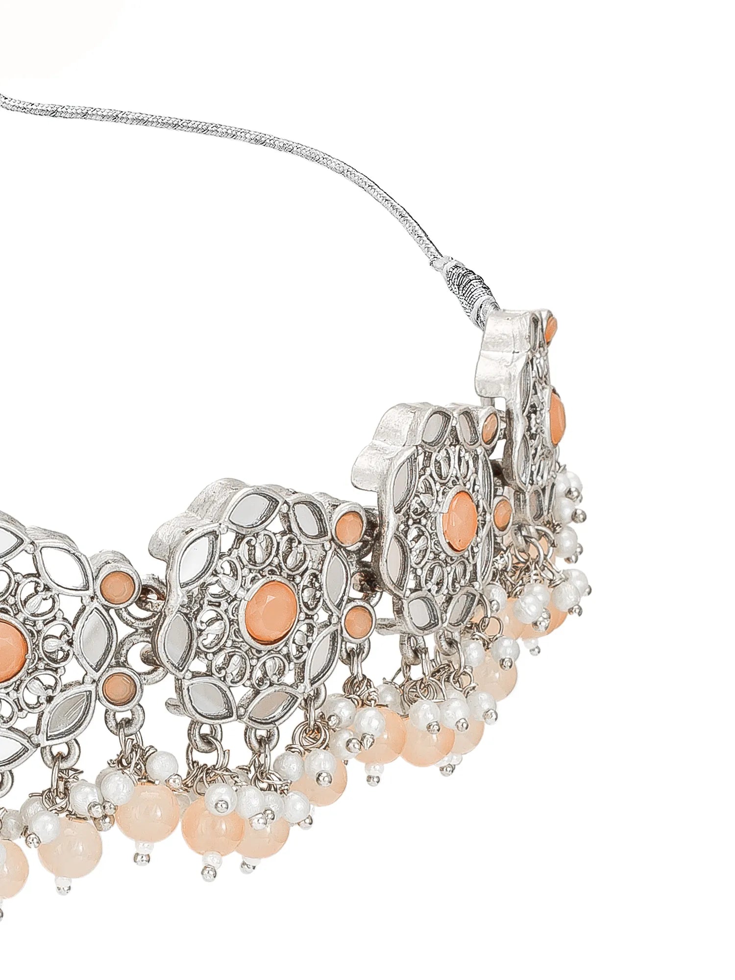 An ornate silver-toned statement collar necklace featuring circular filigree details, peach-colored stone accents, and dangling pearl-like beads on a white background.