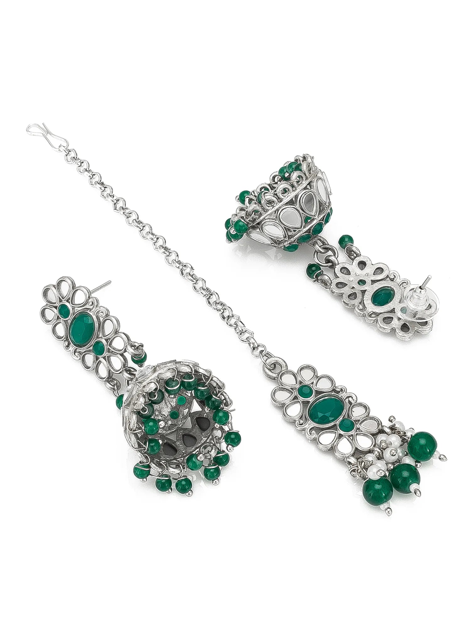 A silver-toned traditional Indian jewelry set featuring a matching chain, earrings, and a maang tikka, embellished with green stones and clear crystals on a white background.